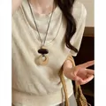 Detail shot of a vintage bohemian woven necklace worn over a cream knit vest. - Large Round Ring Pendant Style (HN12226) / Brown