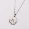 Detailed macro view of silver stainless steel pendant with baby feet and heart text - Sunflower Round Plate Necklace / Steel
