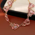 Dettaglio macro di una collana di cristalli geometrici rosa con catena dorata su pelle - Oro-Rosa