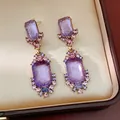 Primo piano di orecchini pendenti vintage con cristalli viola in un portagioie dorato di lusso. - Orecchini / Viola