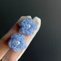 Vue détaillée de boucles d'oreilles fleurs en perles bleues avec une perle blanche. - Bleu