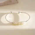 Dettaglio macro di cristallo giallo irregolare su bracciale rigido color argento - Argento-Bianco