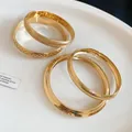 Close-up detail of elegant gold matte and hollow metal bangles set on white plate - Four-Piece Set / Gold