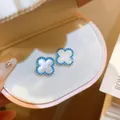 Primo piano di orecchini a quadrifoglio vintage con madreperla bianca e bordo blu - Orecchini a Bottone Quadrifoglio / 30# Argento-Blu