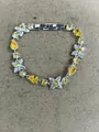 Elegant silver-tone bracelet featuring vibrant yellow pear-cut stones and flower charms - Yellow
