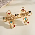 Detail of vintage gold cross earrings featuring lip motif and colorful stones. - Stud Earrings / Gold
