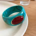 Macro view of bohemian turquoise marble acrylic bangle featuring a large oval red gemstone - Cyan-Wine Red
