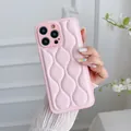 Close-up van roze gewatteerde leren iPhone-hoes met een modieus golfpatroon erop - 14 Pro Max / Roze