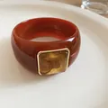 Primer plano de un brazalete de acrílico marrón rojizo con centro decorativo jaspeado - Naranja Y Café