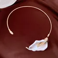 Primo piano di un elegante ciondolo a forma di calla d'oro su una collana girocollo in metallo - Girocollo Calla Bianco / Oro