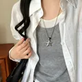 Detail shot of a trendy silver-toned star pendant necklace on a long chain worn by a model - Obsidian Star Pendant / Silver
