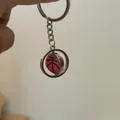 Détail d'un porte-clés basketball rotatif avec anneau en métal argenté et ballon rouge - Basket-ball Rotatif