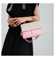 Detail view of a pink and beige woven patchwork crossbody handbag held by a model - Pink