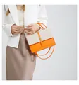 Close-up detail of a stylish orange and straw woven crossbody bag carried by a model - Orange