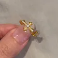Gotischer goldener Kreuzring mit funkelnden Zirkonia auf grauem Stoffhintergrund - Ring (HJZ-0683)