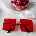 Lunettes de soleil carrées oversize avec verres rouges et pont doré - Style Carré Sans Monture Verres Rouges Accent Métallique