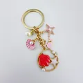 Detailed view of a gold-tone ocean-themed keychain with starfish and seashell charms - Golden Pink Dolphin (Q1539)