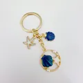 Close-up of a golden ocean-themed keychain featuring blue shell and white starfish charms - Golden Dark Blue Shell (Q1540)