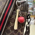 Miniature red leather baseball and wooden bat keychain hanging from a brown bag. - 2CM Red Ball 7.5CM Short Bat