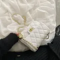 White quilted flap bag with golden ball chain and metallic lock on black fuzzy fabric - White