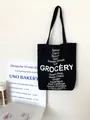 Minimalist black canvas tote bag featuring white grocery text print for women - Black