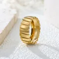 Close-up macro detail of a vintage gold ribbed stainless steel ring on a white stone background - US 7 / Gold