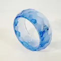 Nahaufnahme der geometrisch facettierten Oberfläche eines blauen Harzarmreifens - Blau