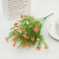 Close-up of artificial orange jasmine bundle with green leaves in a white vase - Sunset Orange