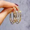 Detailed macro view of gold hoop earrings encrusted with sparkling cubic zirconia - Multi-Layer Overlap Pave Style (E2596 Gold) / 925 Silver Needle / Gold