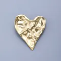 Elegante broche de acero inoxidable con forma de corazón dorado y acabado martillado. - Dorado