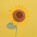 Handmade crochet sunflower with yellow petals and green leaf on yellow background - Yellow-14 Petals Single-layered Seeded Sunflower Stem