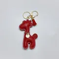 Detailed close-up of a red leather giraffe bag charm with gold tassel and Lucky Girl tag - With Keychain Tassel / Burgundy