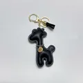 Detailed view of a black leather giraffe keychain charm with gold hardware and tassel - With Keychain Tassel / Black