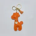 Detailed view of bright orange leather giraffe keychain with gold tassel and charm - With Keychain Tassel / Orange