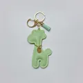 Detail view of a mint green cartoon giraffe faux leather keychain with gold hardware and tassel. - With Keychain Tassel / Green