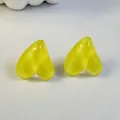 Close-up of translucent candy yellow heart-shaped earrings on a plain white surface. - Candy Yellow (32439-ear-yellow-EP)