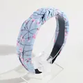 Stylish light blue knotted headband with pink floral pattern on a clear acrylic stand - Blue Floral Print