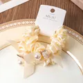 Eleganter beigefarbener Scrunchie mit Perlen und Schleifen auf einer Displaykarte. - 2er Pack / Beige