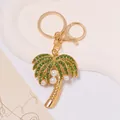 Detailed view of a gold coconut tree keychain with green crystals and white pearls. - Gold Coconut Tree With Green Rhinestone