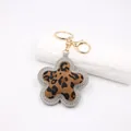 Close-up of leopard print flower keychain with gold-tone metal clasp and grey stitching - Gray