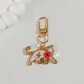 Detail view of cat-shaped gold metal keychain with red dried flowers in clear resin - Pink Flower Kitten