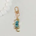 Close-up of a cat-shaped gold keychain filled with blue dried flowers in clear resin - Blue Flower Cat