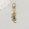 Close-up of cat-shaped resin keychain with embedded dried flowers and golden clasp - Three Flowers Cat