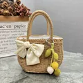 Handgewebte Stroh-Handtasche mit eleganter weißer Schleife und Obst-Anhänger - Dekorierter Stil / Kaffeebraun