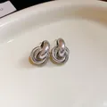Elegant intertwined circular silver stud earrings with a high-shine metallic finish. - Metal Knot Stud Earrings with 925 Sterling Silver Earring Post / Silver