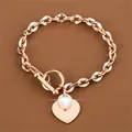 Primo piano dettagliato del bracciale in acciaio oro rosa con cuore e chiusura a levetta - Oro rosa
