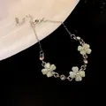 Elegant silver-toned bracelet featuring three pale green cat's eye flower charms - Bracelet / Green