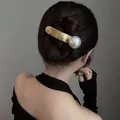 Elegant gold metallic hair clip featuring a large white pearl on a female model's hair - Gold (B3405)