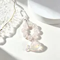 Dettaglio macro di un portachiavi a balena iridescente con catena di perle decorative - Bianco Iridescente