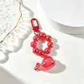 Detailed view of a red translucent whale keychain with glossy beads and metal clasp - Red